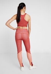 Haut court de sport rouge et leggings taille haute avec dégradé de couleurs. Les leggings présentent des panneaux latéraux contrastants et des accents aux chevilles.