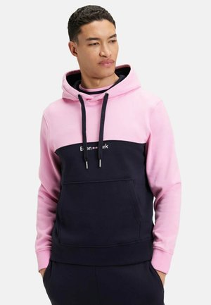 Sweat-shirt à capuche avec un haut rose et un bas bleu marine, fabriqué en tissu doux, doté d'une poche frontale et de cordons de serrage. Logo "Even&mark" affiché.