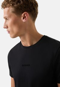 Černé bavlněné tričko s kulatým výstřihem, krátkými rukávy a jemně vyšitým logem "BOGNER" na prsou. Hladká textura.