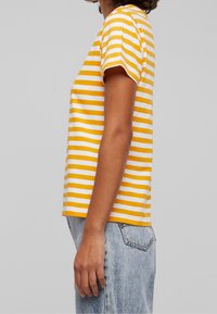 Yellow and white striped t-shirt with short sleeves, crafted from cotton, featuring a relaxed fit and simple crew neckline.