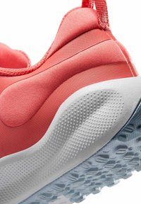 Chaussure de sport corail avec une tige texturée et des accents lisses. Dotée d'une semelle en caoutchouc blanc avec une adhérence à motif pour plus de traction.