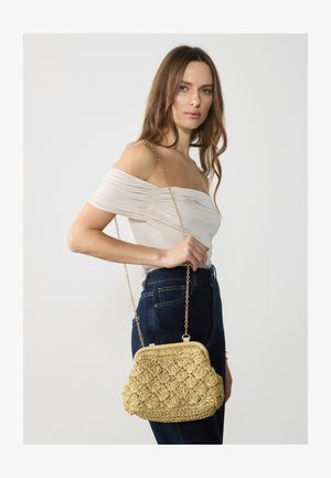 Tkaná slamenná kabelka v svetlo béžovej farbe, s oblým tvarom, klipovým uzáverom a zlatým reťazovým popruhom. Textúrovaný povrch s diamantovým vzorom.