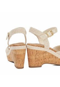 Wedge sandals with a cork heel, beige woven textile straps, adjustable ankle buckle, and open toe design. Textured and lightweight finish.