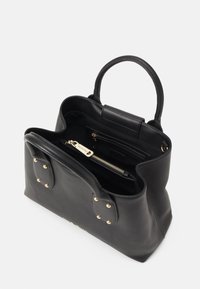 Svart läder tote-väska med guldfärgad hårdvara, två ovandelshandtag och inre fickor; slät textur, rektangulär form och dekorativa nitar.