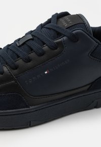 Sneaker blu navy realizzato in materiali in pelle e suede, chiusura con lacci, suola in gomma e logo "TOMMY HILFIGER" impresso sul lato.