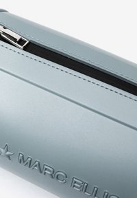 Pochette cilindrica azzurra realizzata in materiale liscio, con hardware argentato e logo impresso. Cerniera lungo il bordo superiore con foderatura nera.