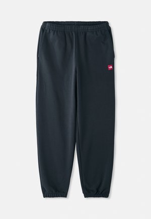 Calças de fato pretas feitas de tecido suave, com um cós elástico, punhos de tornozelo e um pequeno emblema vermelho de logotipo na lateral.