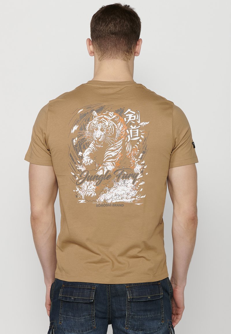 T-shirt à manches courtes beige avec un graphisme de tigre, des accents blancs et oranges, le texte "Jungle Fun" et une coupe décontractée.