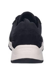 Czarne sneakersy z teksturowaną cholewką, zamszowymi akcentami, wyściełanym kołnierzem i białą podeszwą z wytłoczonym logo marki na pięcie.