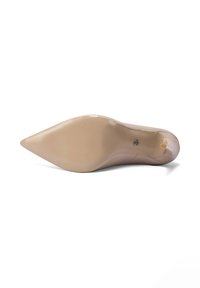Zapato de tacón alto de charol beige con punta puntiaguda, mostrado desde la suela con una pequeña punta en el tacón y un detalle de logotipo cerca del arco.