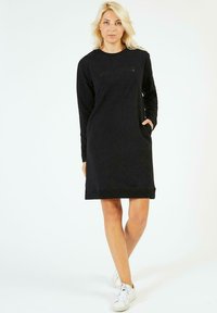 Robe sweat noir à manches longues, avec poches latérales et col rond. Dotée d'un subtil logo sur le devant.