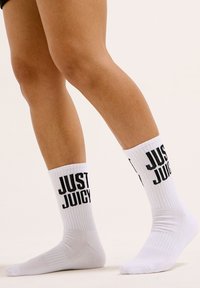 Calzini bianchi in cotone al ginocchio con texture a coste e testo nero "JUST JUICY" stampato su ciascun lato.