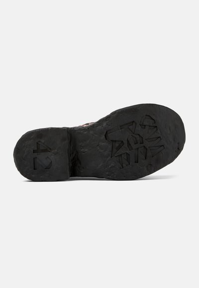 Suola di scarpa in gomma nera con motivo di battistrada testurizzato; presenta forme geometriche sollevate e marchi del brand sul tallone e sulla parte centrale della suola.