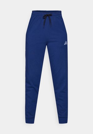 Blue cotton joggers with an elastic waistband, adjustable black drawstring, and a small white logo on the left thigh. Fitted design.