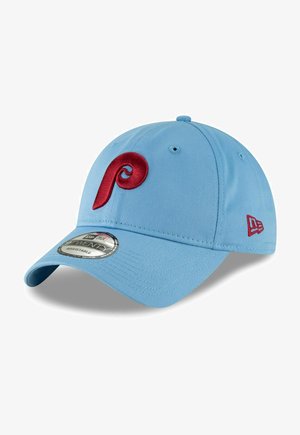 Gorra de béisbol de color azul claro hecha de tela con visera curvada. Presenta un logo bordado en rojo y una etiqueta circular en la visera.