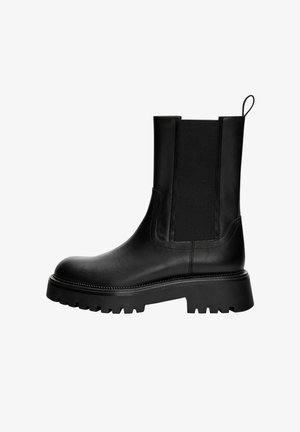 Černá kožená kotníková bota s hladkým povrchem, elastickými bočními panely a robustní podrážkou s hlubokým vzorem. Očko na zadní straně pro snadné nazouvání.