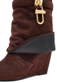Brown suede wedge boot with a folded design, featuring a decorative gold hardware accent and a contrasting black fabric band.