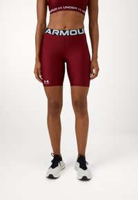 Shorts de sport bordeaux avec un design ajusté, taille élastique arborant "ARMOUR" en gris, et accent de logo blanc en bas à gauche.
