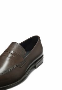 Brauner Lederloafer mit strukturiertem Stoffeinsatz, breitem Riemendetail, rundem Zehenbereich und flachem Absatz. Minimale Markenkennzeichnung und glatte Oberfläche.