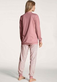Long-sleeve pink cotton top with a crew neck, paired with patterned pajama pants featuring a floral design in pink and blue hues.