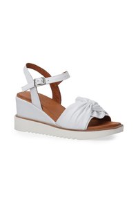 Witte wedge sandaaltjes met een geknoopt ontwerp aan de voorkant, verstelbare enkelriem en een textuurzool voor grip. Bruine leren binnenzool zichtbaar.