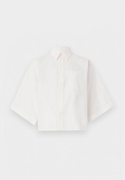 Λευκό κοντό πουκάμισο με κουμπιά από ελαφρύ ύφασμα, με γιακά, κοντά μανίκια και μία τσέπη στο στήθος.
