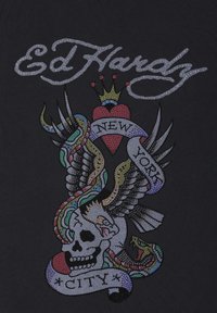 Black fabric features a colorful, rhinestone-studded graphic of a skull, eagle, snake, and heart, with the text "Ed Hardy" and "New York City."