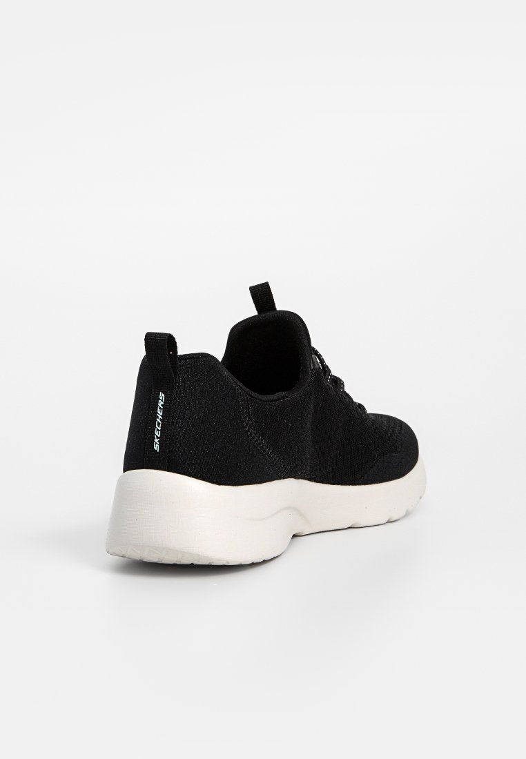 Zapatilla deportiva negra con una parte superior de tejido texturizado, suela de goma blanca y una tira en el talón. Presenta un diseño de cordones y detalle del logo de la marca.