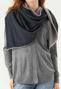 Écharpe bleu foncé et gris clair drapée sur un pull gris, présentant une texture douce et des bords cousus contrastants.