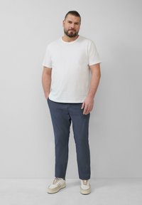 Witte short-sleeve t-shirt, donkerblauwe slim-fit broek en beige sneakers. Gladde stof met een casual ontwerp, geen patronen.