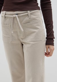 Beige corduroy broek met een relaxed fit, voorzien van twee frontzakken, een trekkoord in de taille en subtiele textuurlijnen.