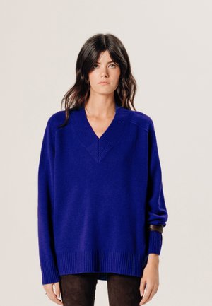V-Ausschnitt, übergroßer Pullover in strahlendem Blau, mit gerippten Bündchen und Saum. Hergestellt aus weichem Material mit glatter Textur und lockerer Passform.