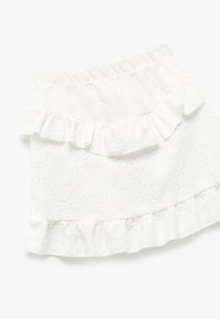 Falda blanca con volantes y un diseño texturizado, con detalles bordados. Cintura elástica y volantes en capas a lo largo del dobladillo.