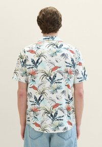 Short-sleeve shirt in lightweight fabric featuring a tropical print with palm leaves in blue, green, orange, and yellow. Buttoned collar, relaxed fit.