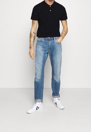 Navy polo shirt with two buttons, light blue denim jeans, and white sneakers featuring a black star logo. Classic fit with rolled cuffs.