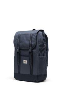 Mörkblå ryggsäck i hållbart material, med klaffstängning, justerbara remmar och en frontficka med logotyp.