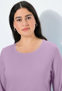 Lavendelfarbenes Langarmshirt mit Rundhalsausschnitt, aus glattem Stoff gefertigt. Verfügt über eine dezente Textur und eine normale Passform.