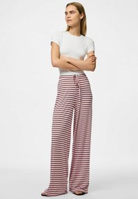 Streepbroek met wijde pijpen in roze en zwart, met een elastische tailleband en een trekkoord, gecombineerd met een aansluitend wit T-shirt met korte mouwen.