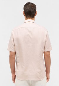 Korte mouwen, lichtroze linnen shirt met een subtiele textuur en een achterste schoudernaad. Heeft een standaardkraag en een licht gebogen zoom.
