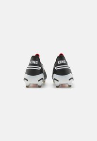 Botas de fútbol negras con el texto "KING" en blanco, detalles en rojo y una parte superior texturizada. Con una suela blanca rígida con tacos para mayor tracción.