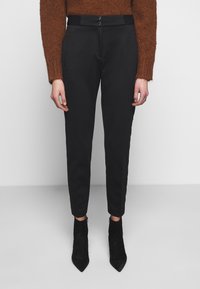 Pantaloni neri su misura con una vestibilità slim, caratterizzati da una texture liscia, due tasche frontali e una vita con due bottoni.