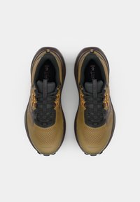 Baskets de sport en mailles marron avec des accents sombres. Les caractéristiques comprennent un dessus texturé, des lacets contrastants et une semelle en caoutchouc robuste. Branding minimal visible.