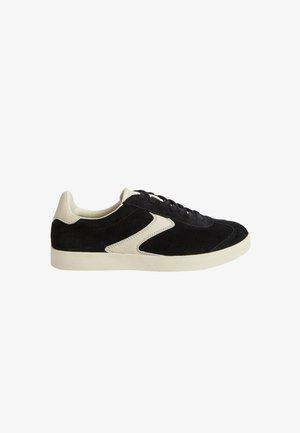 Zapatillas de ante negro con detalles en crema, diseño de cordones, costuras en contraste y suela de goma. Forma clásica de zapato deportivo.