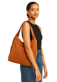 Borsa a spalla in pelle scamosciata marrone con una texture morbida, design spazioso e spallacci robusti, indossata in modo casual su una maglietta nera e jeans blu.