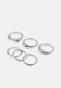 Zestaw sześciu srebrnych pierścionków, z różnymi wzorami: gładkie, skręcane, z koralikami i fakturowane. Mieszanka kształtów, w tym okrągłe i faliste krawędzie.