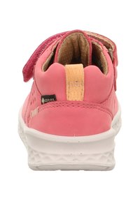 Rosa Walking-Schuh mit einem weichen, wildlederähnlichen Obermaterial, Klettverschluss, Mesh-Futter und einer weißen Gummisohle mit strukturiertem Muster.