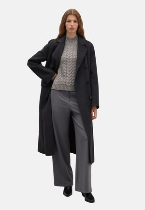 Dark gray wool coat with a double-breasted design, paired with a textured light gray sweater and wide gray trousers. Black ankle boots complete the look.