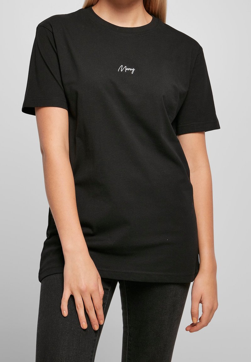 Černé bavlněné tričko s krátkými rukávy, kulatým výstřihem a bílou výšivkou "Merry" na hrudi. Měkká textura, uvolněný střih.