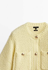 Dziewiżowany żółty kardigan o teksturowanej tkaninie, z okrągłym dekoltem, dwiema przednimi kieszeniami i dekoracyjnymi guzikami w złotym odcieniu.