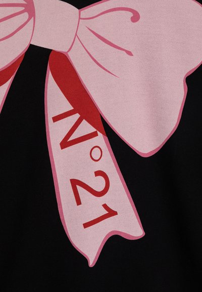 Svart stoff har et stort rosa sløyfe-motiv med et rødt hengende klistremerke som viser "N°21". Designet inkluderer glatte teksturer og sterke farger.